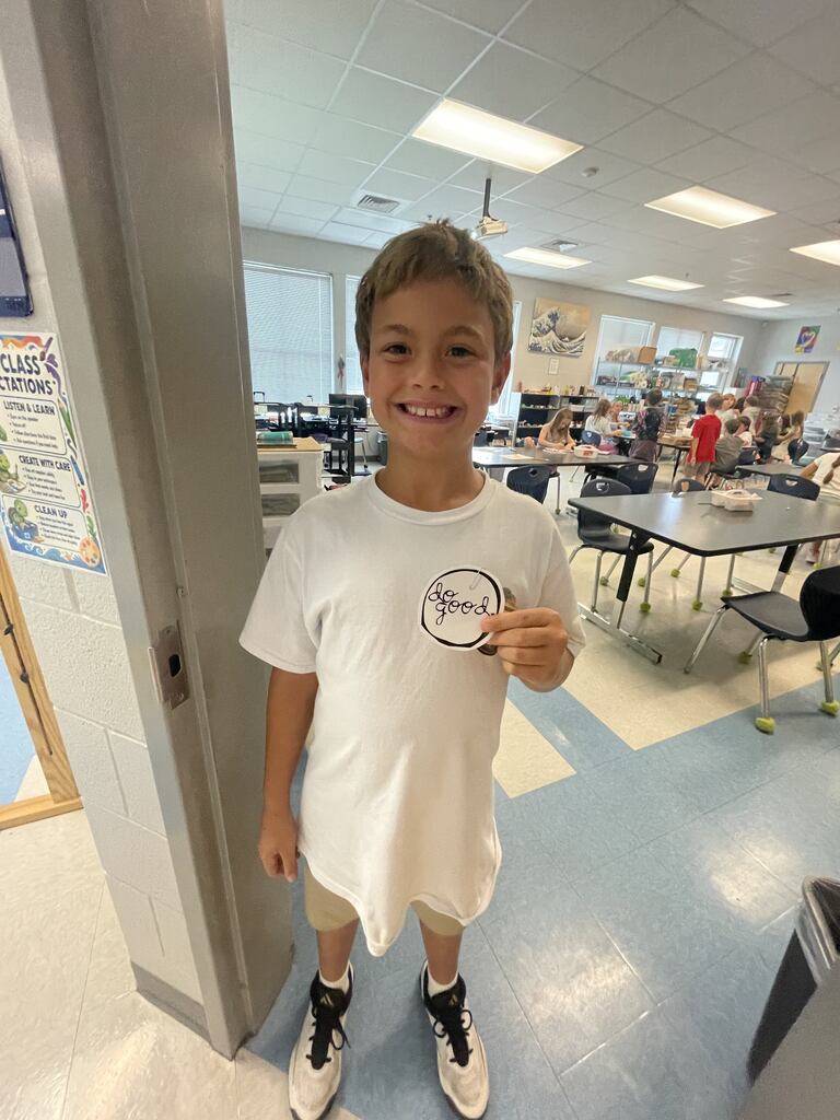 student holding a "do good" sticker