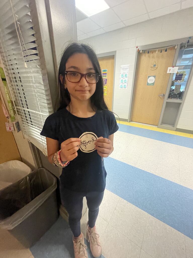 student holding a "do good" sticker