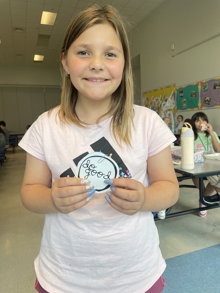 student holding a "do good" sticker