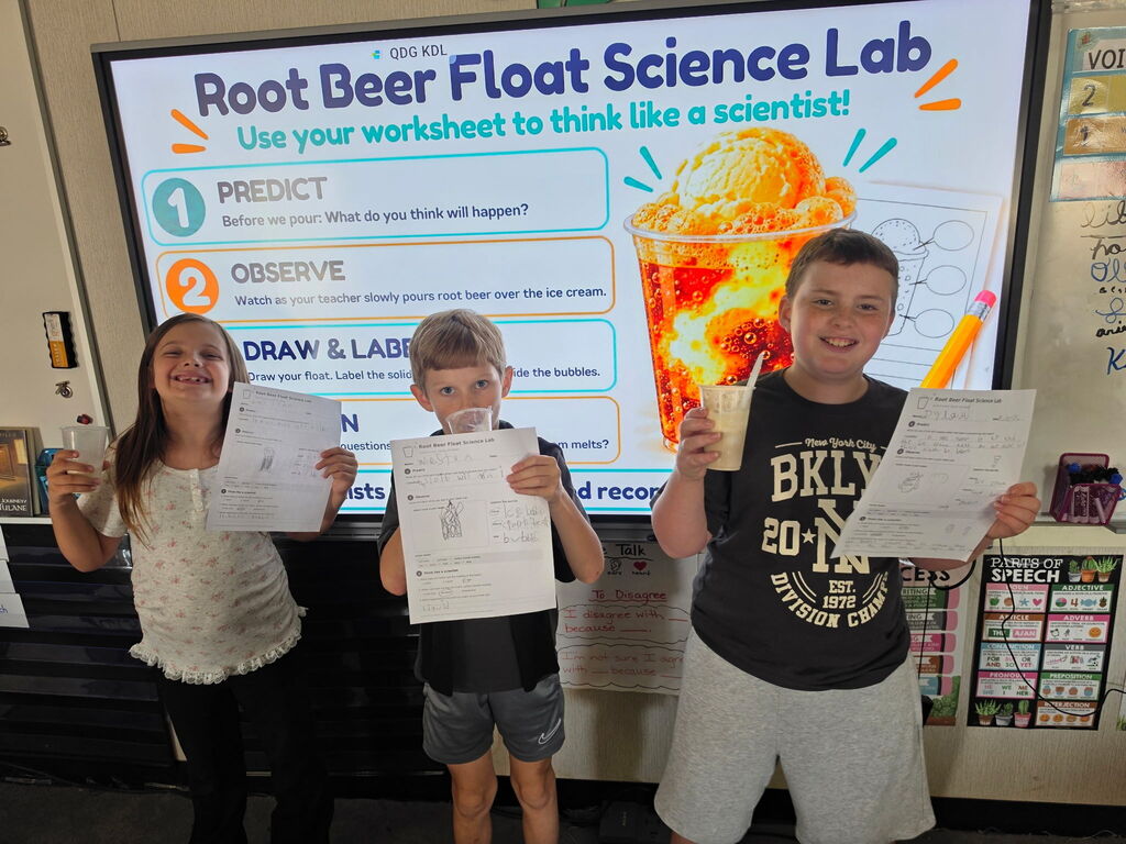 3rd grade students holding up root beer float science lab materials 