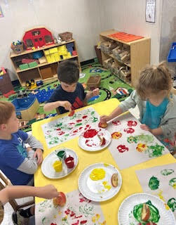 preK students painting with apples