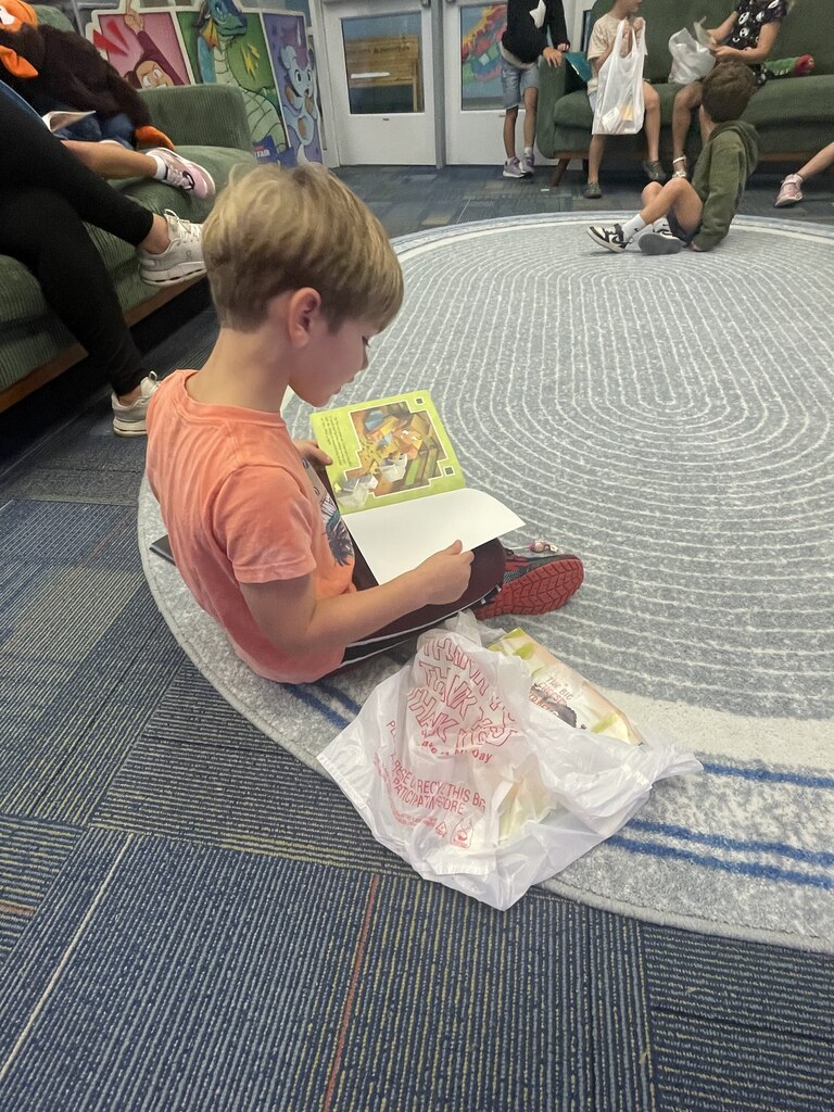 students sitting on the couch reading book fair books