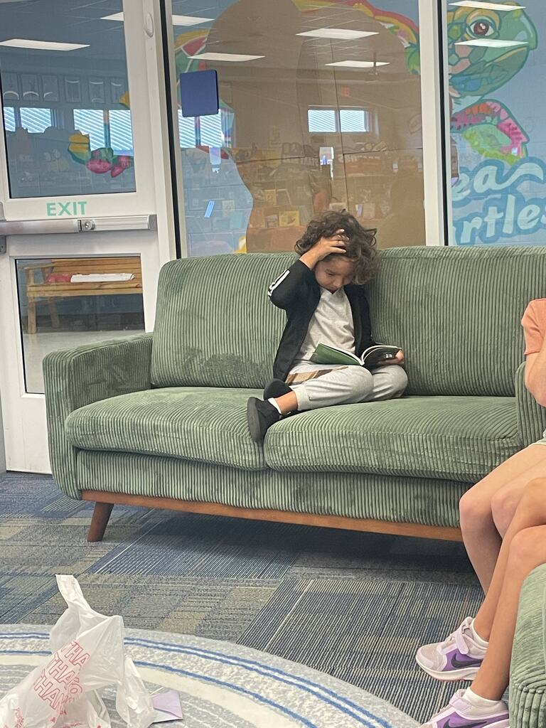 students sitting on the couch reading book fair books