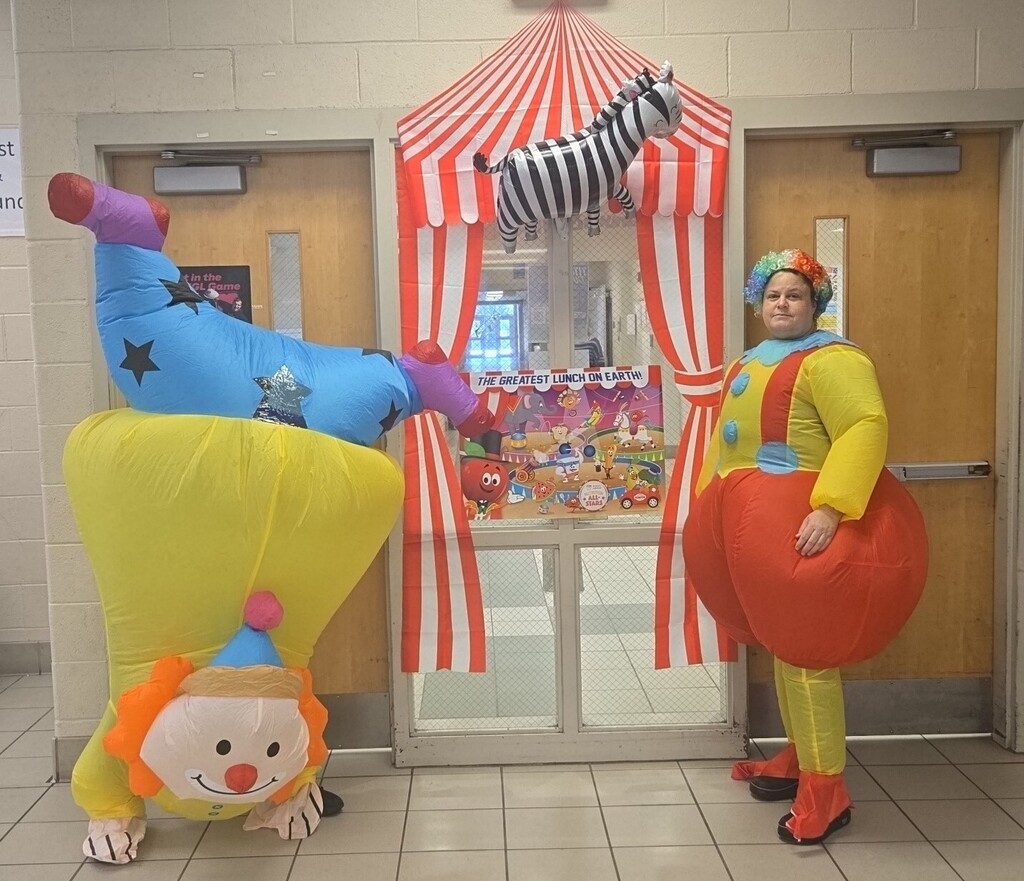 Child nutrition staff standing at cafeteria door in festive clown circus costumes.