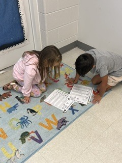 first grade students working in pairs on a readers theater assignment