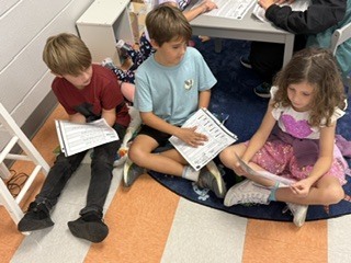 first grade students working in pairs on a readers theater assignment