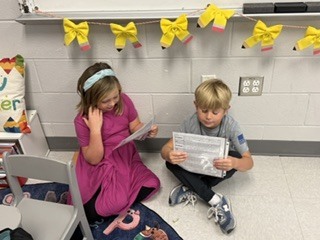 first grade students working in pairs on a readers theater assignment