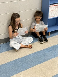 first grade students working in pairs on a readers theater assignment