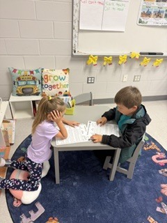 first grade students working in pairs on a readers theater assignment