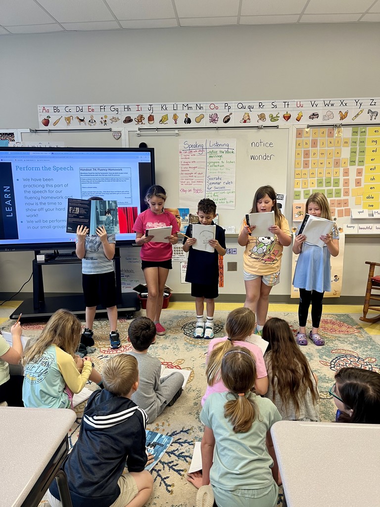 2nd graders standing up in front of class reading from a book