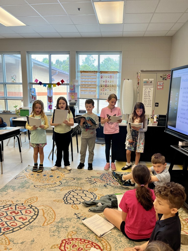 2nd graders standing up in front of class reading from a book