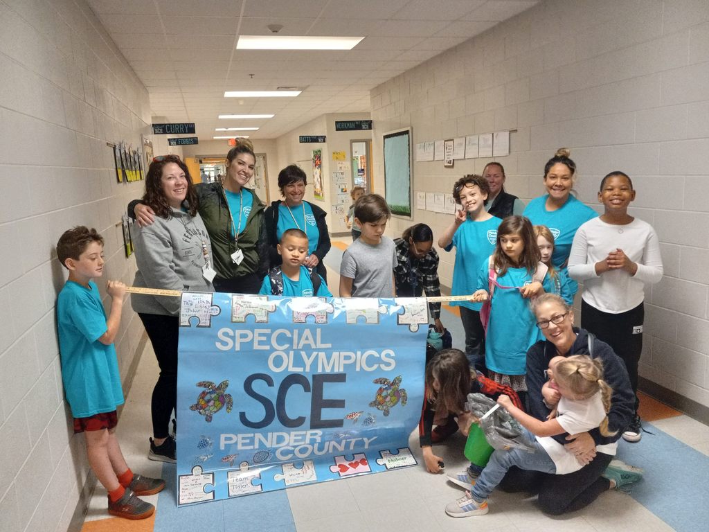 EC students and teachers standing in front of special Olympics flag