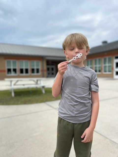 kindergarten kid blowing bubbles