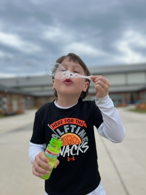 kindergarten kid blowing bubbles