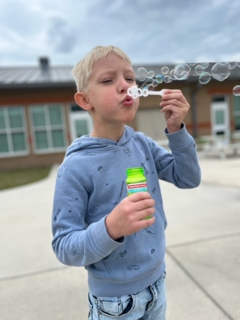 kindergarten kid blowing bubbles