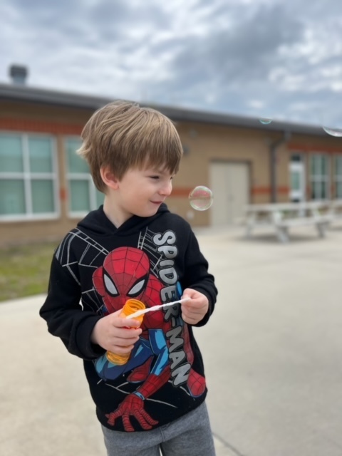 kindergarten kid blowing bubbles