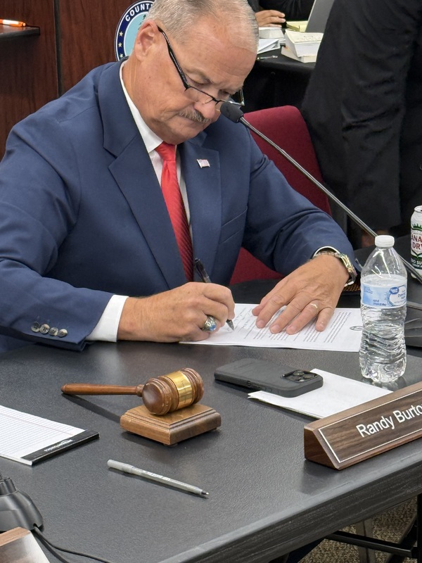 Chair Burton signs the updated budget