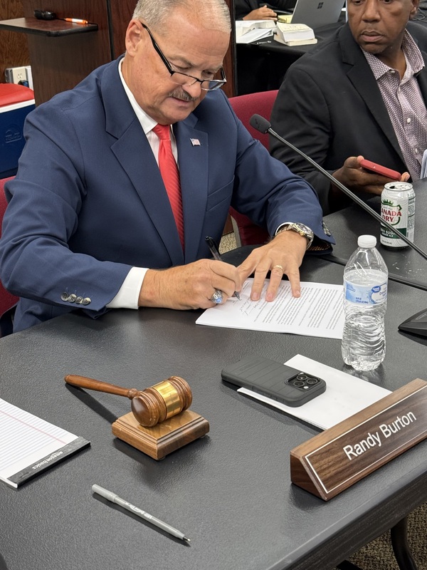 Chair Burton signs the updated budget