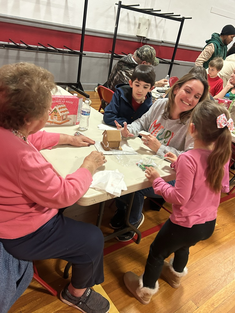Families working together to build a gingerbread house. 