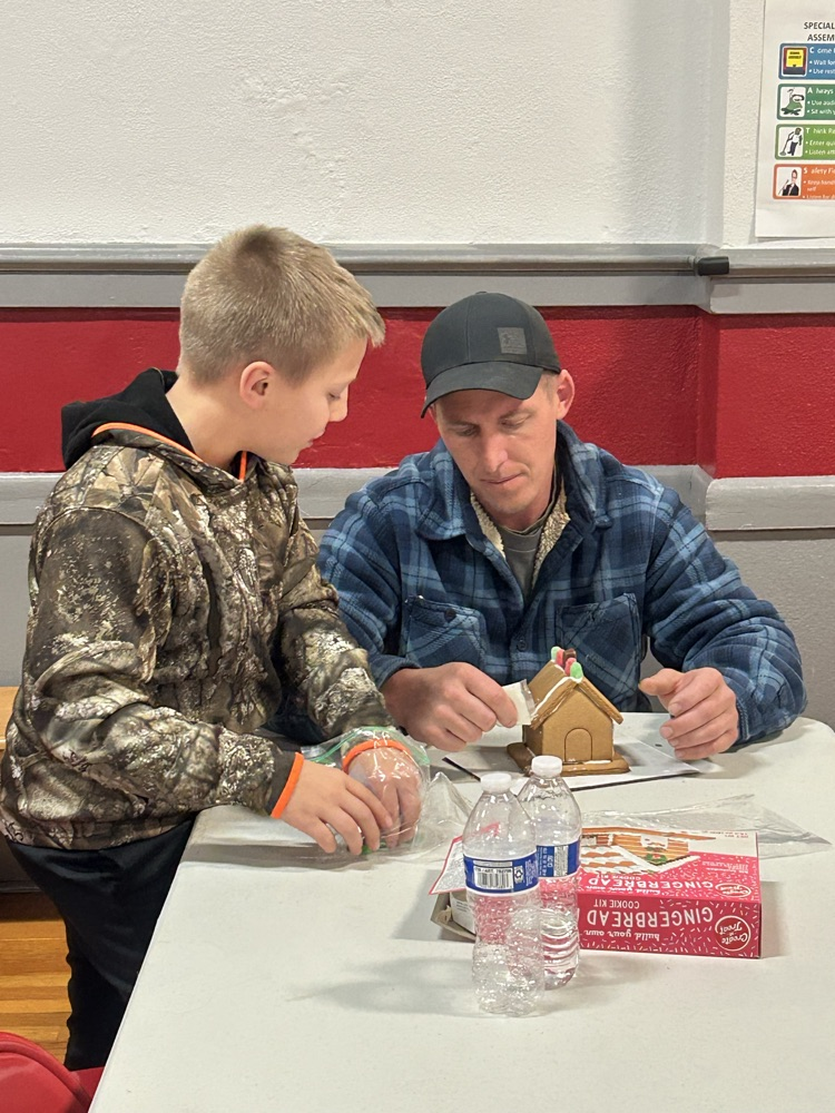 Families working together to build a gingerbread house. 