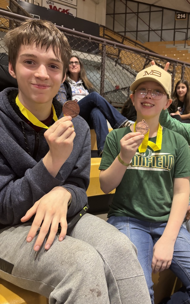 Two students smiling with the medals they won at the competition in hand.