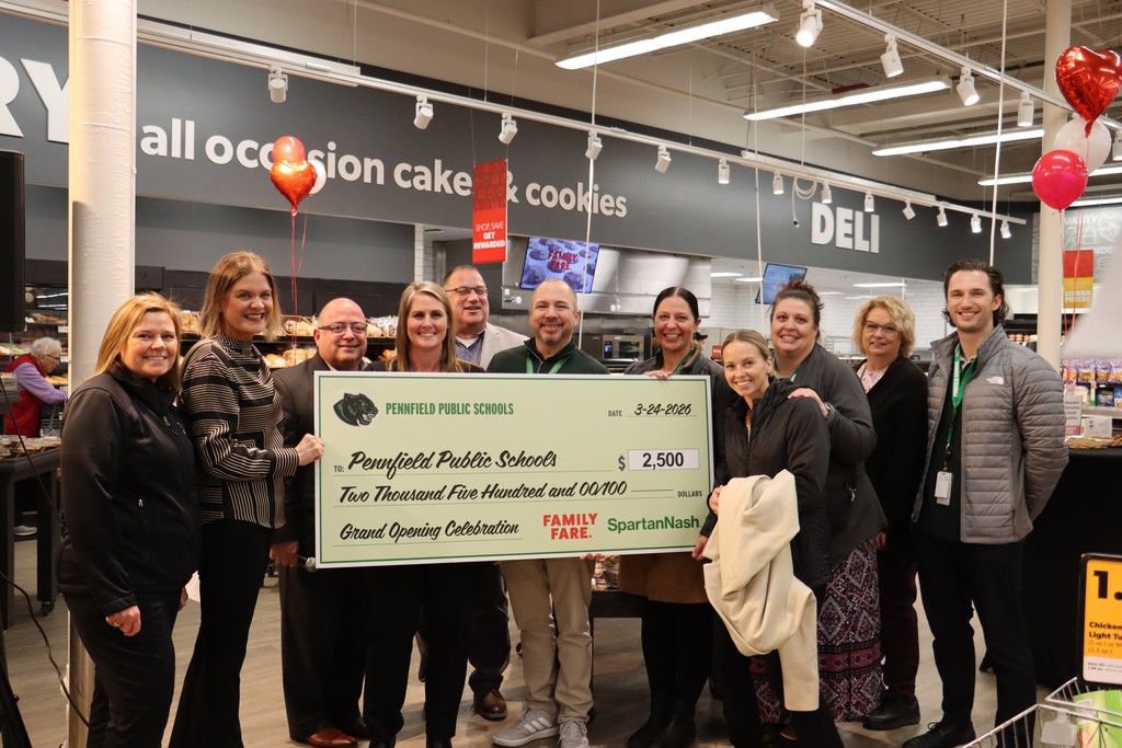 Pennfield Schools Staff and Family Fare owner and Manager smiling behind giant check for Pennfield schools for the amount of 2,500 from Family Fare.