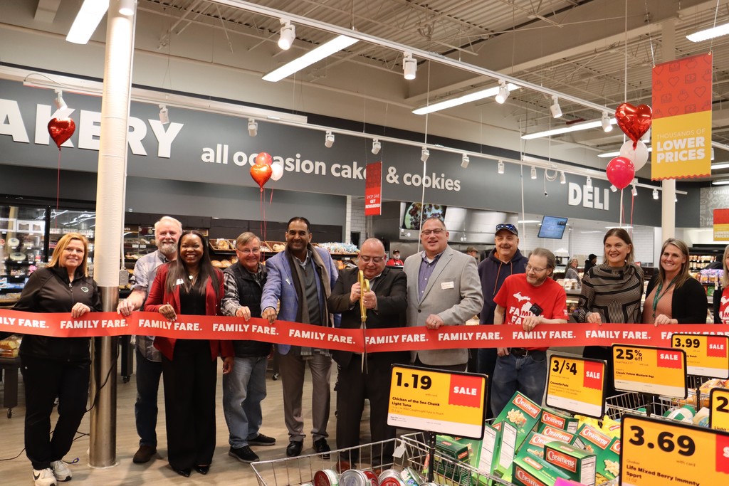 Family Fare Staff, Pennfield Schools Staff, and Community members cutting family fare ribbon with giant scissors for grand reopening