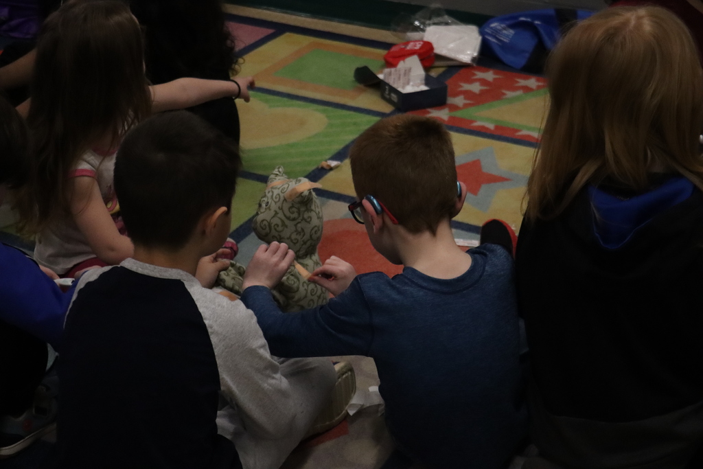 2 students putting a bandaid on stuffed animal