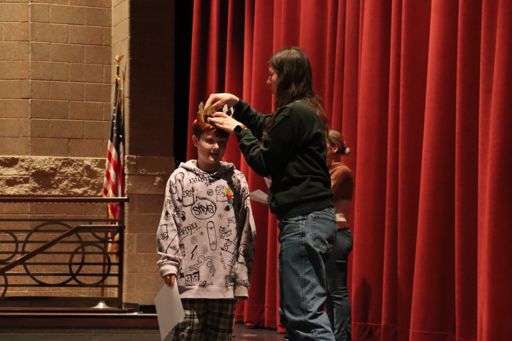 Student being crowned on stage by teacher