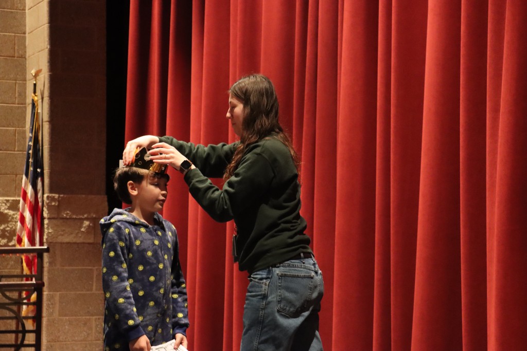 Student being crowned on stage by teacher
