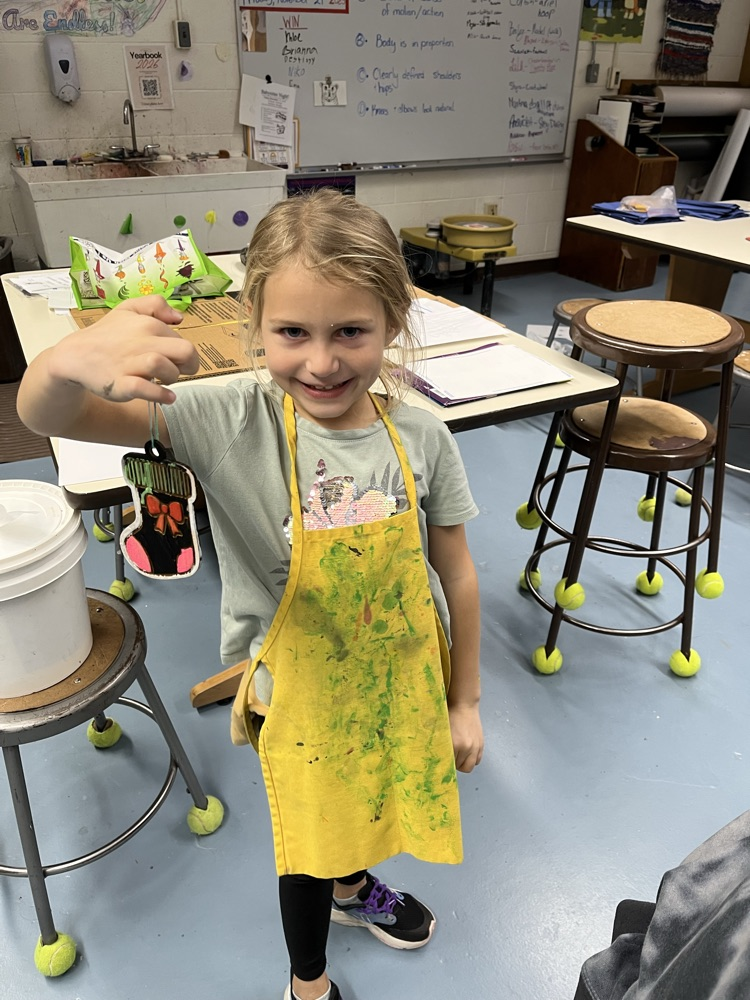 a girl holding up a painted ornament 