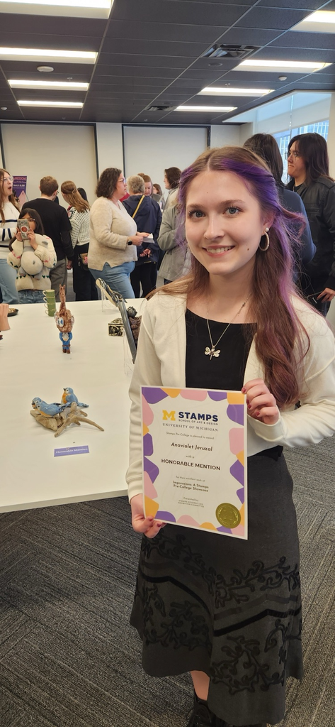 Anaviolet holding her certificate next to her sculpture, "birds.”