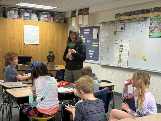 Kari Wilson (Oceana Conservation District) shows the 3rd grade students white pine seedlings and how to plant them