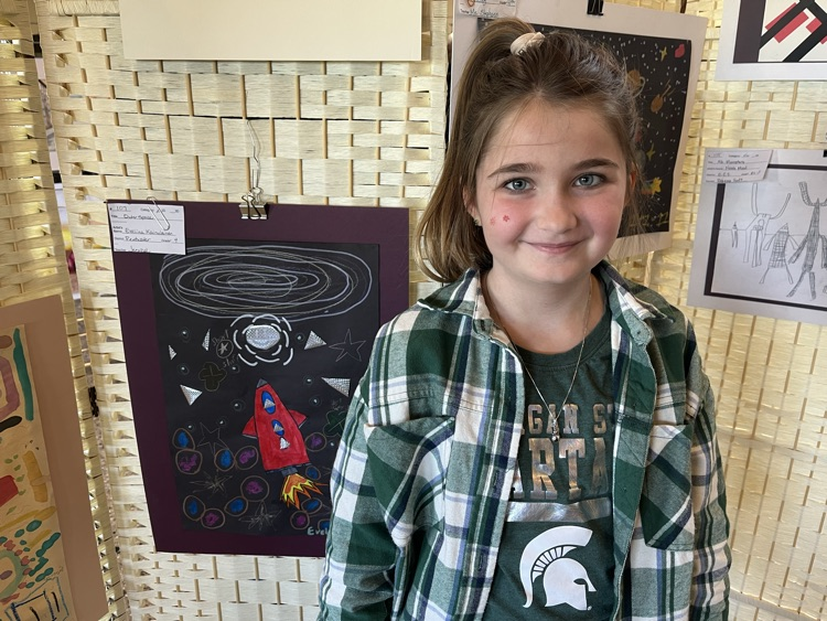 Evaliina stands in front of her space drawing. 
