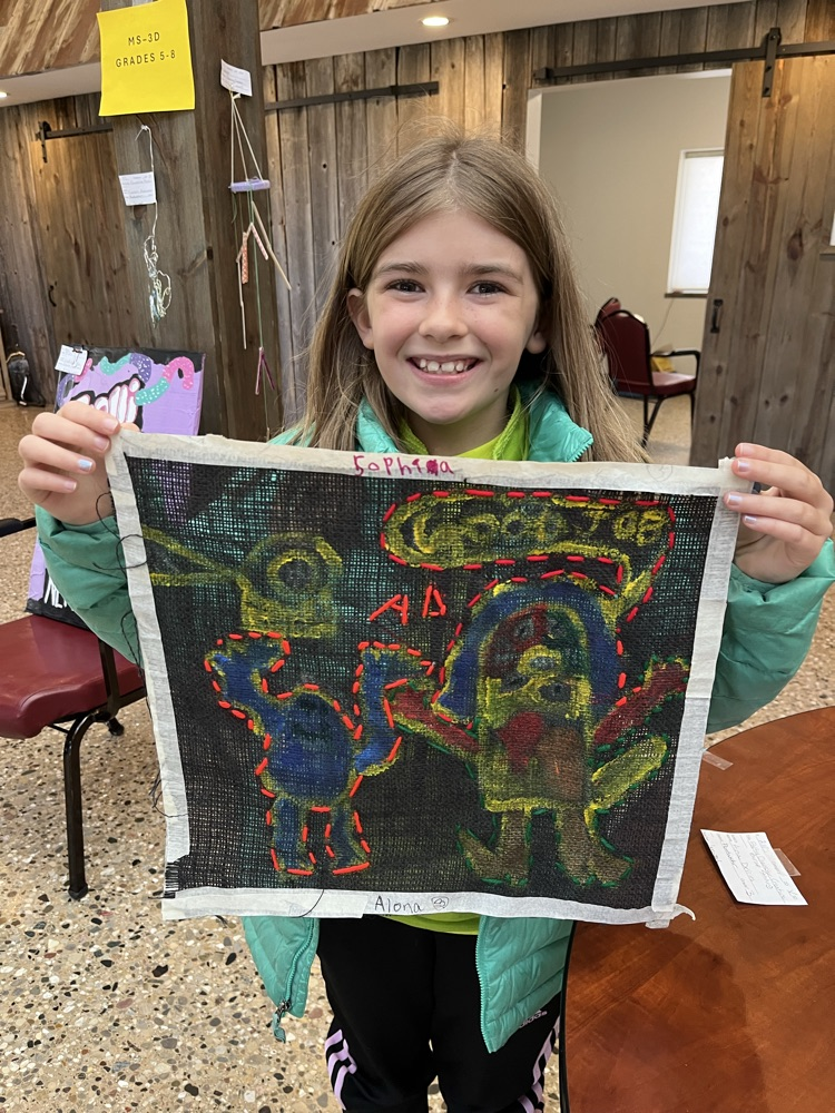 Alona holds up her stitching. 
