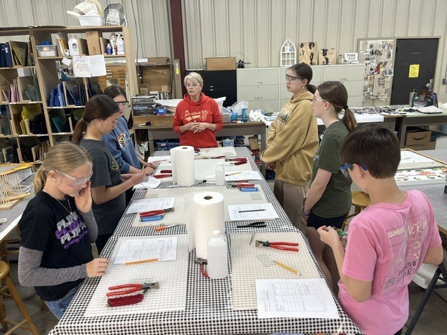 Students listening to instructions about glass art.