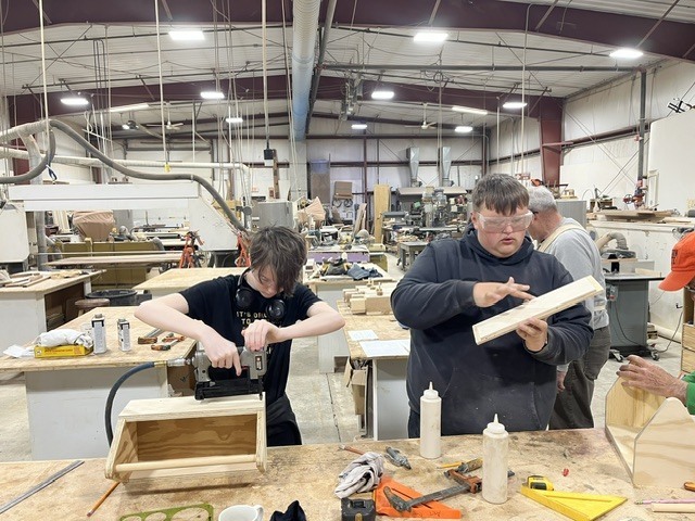 Students drilling wood and using glue. 