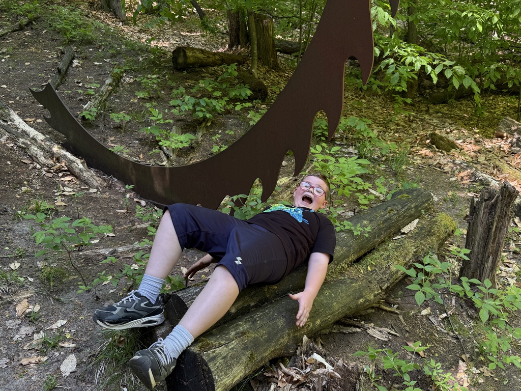 A student pretends to fall under a sculpture at MI Legacy Art Park