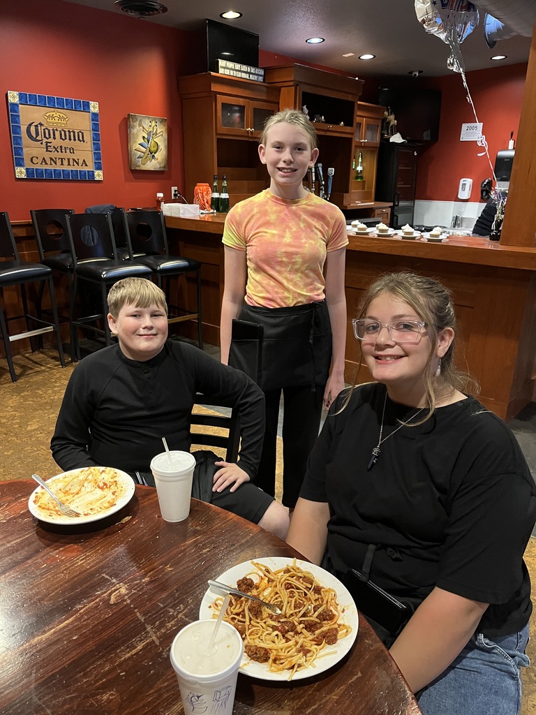 Three students take a break to eat their spaghetti.