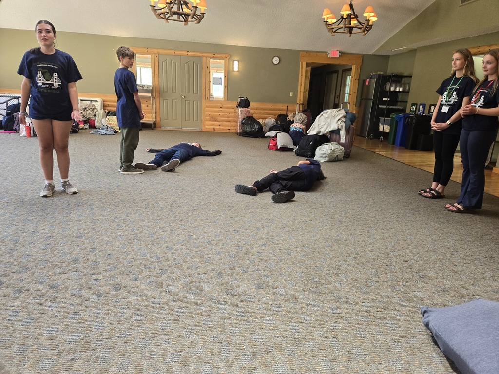 Middle schoolers practicing their skit so some are laying down and some are standing.