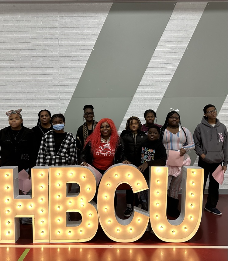7 students and 3 staff members standing behind large illuminated letters of HCBU