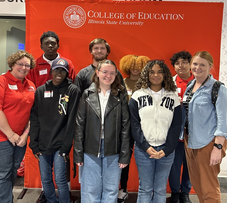 7 students and 2 staff posing with future teacher signs