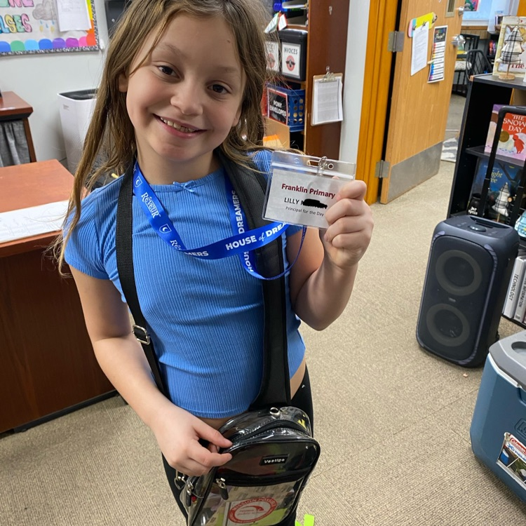 student holding principal for a day badge