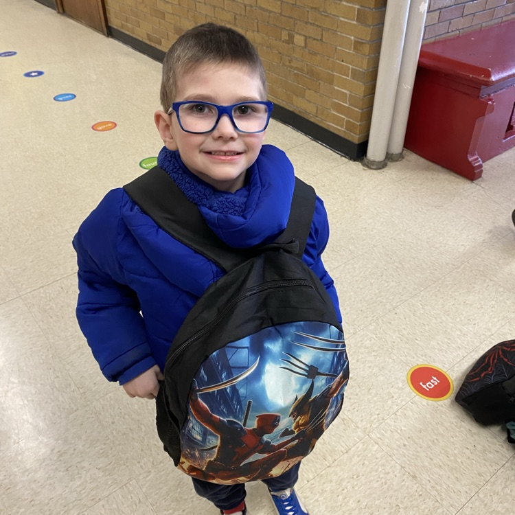 student wearing clothes, coat, and backpack backward
