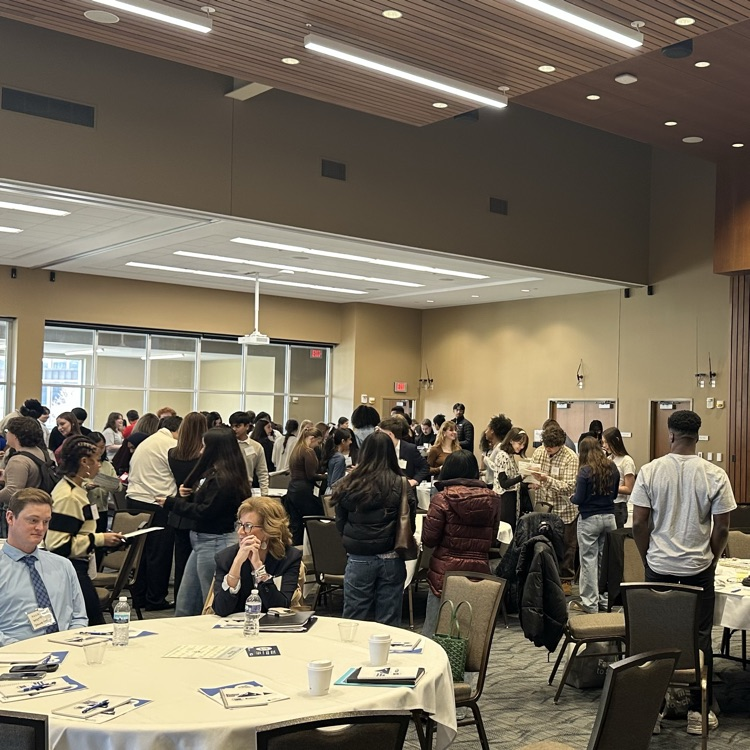 large room with students walking around talking with other students completing "get to know you” bingo