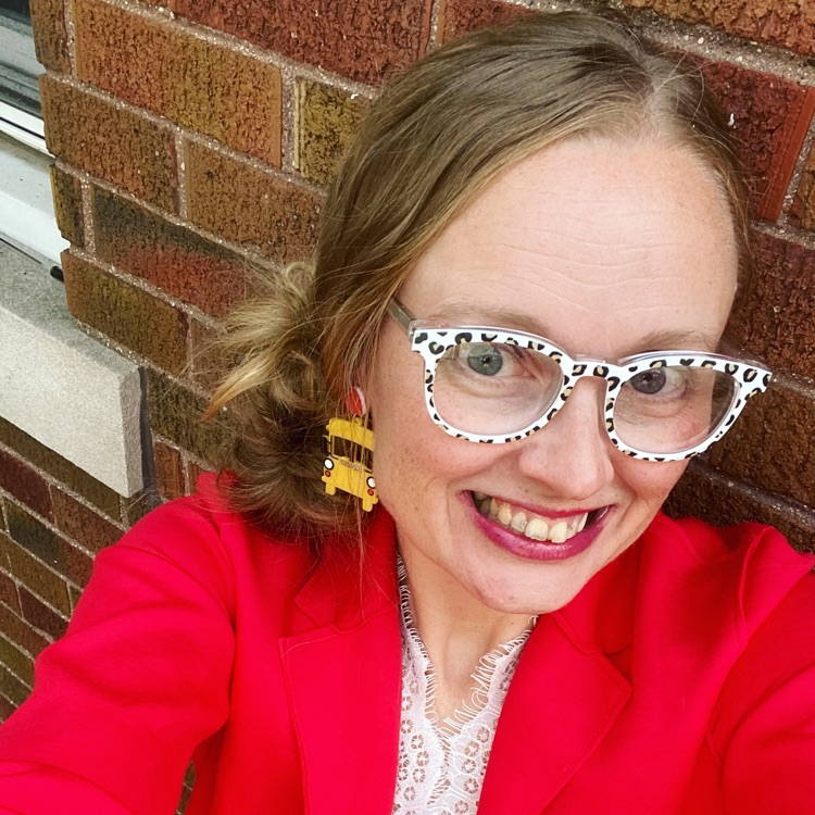 picture of principal wearing red blazer and white lace top smiling