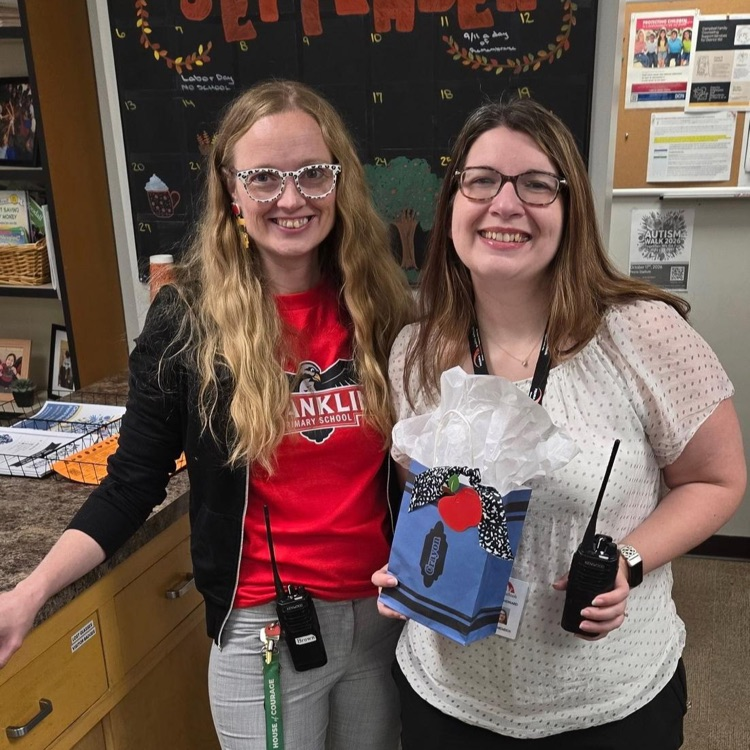 picture of school principal and BoE member holding radios and a gift bag
