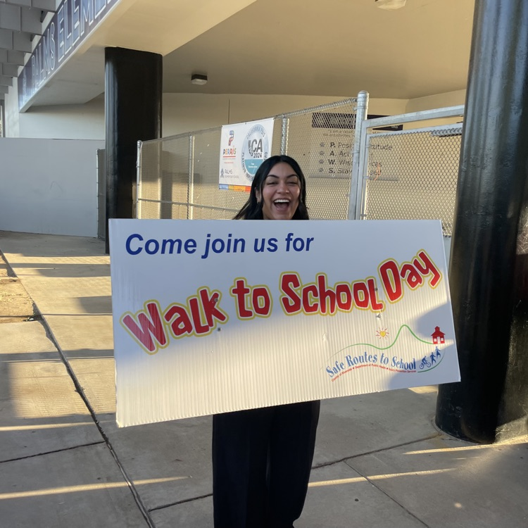 teacher welcoming students with a sign
