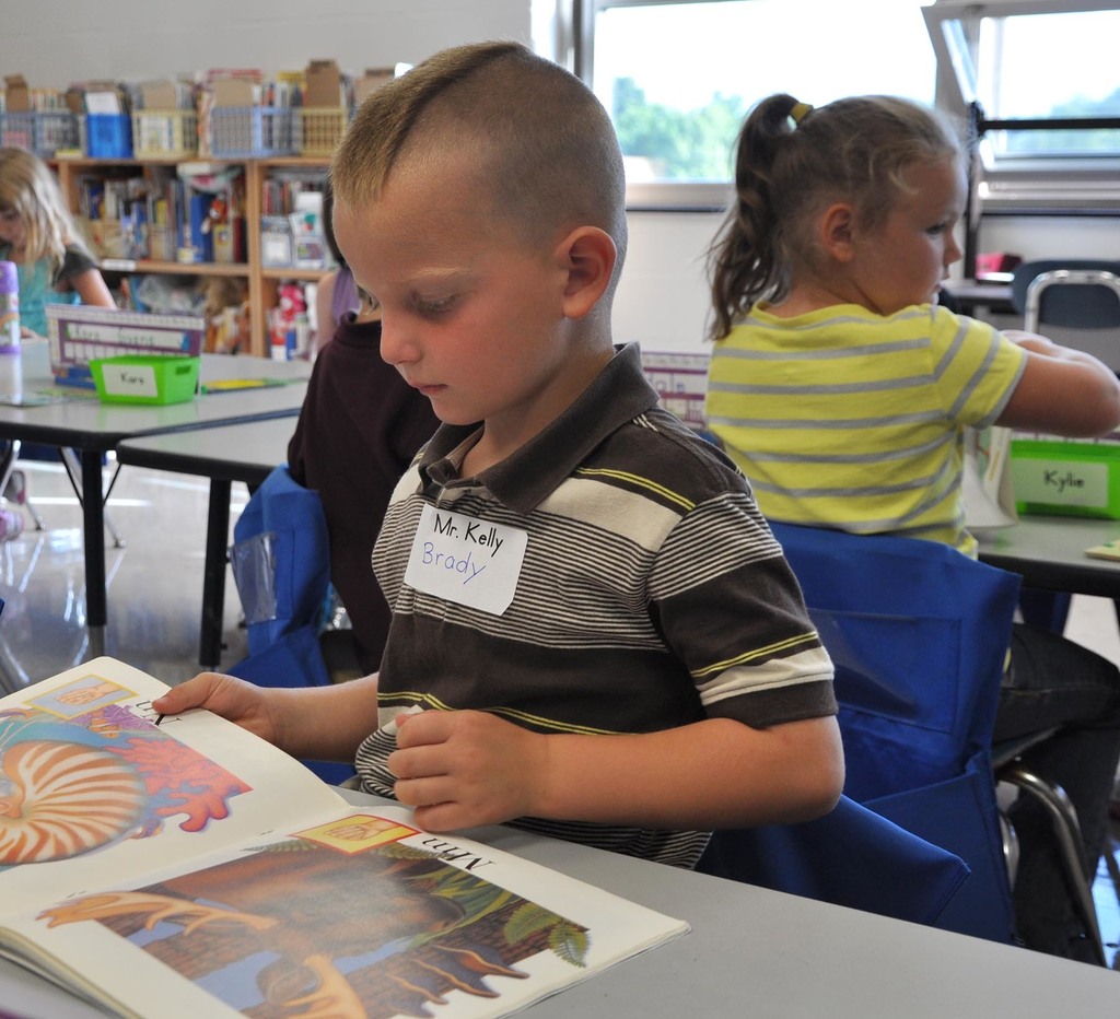 An elementary student flipping through a book in school. 