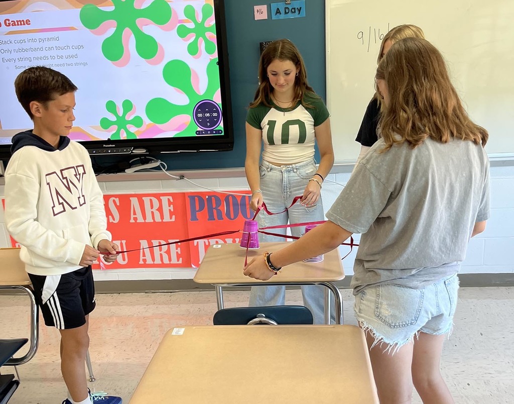 Four jr. high students work together on stacking several cups. 